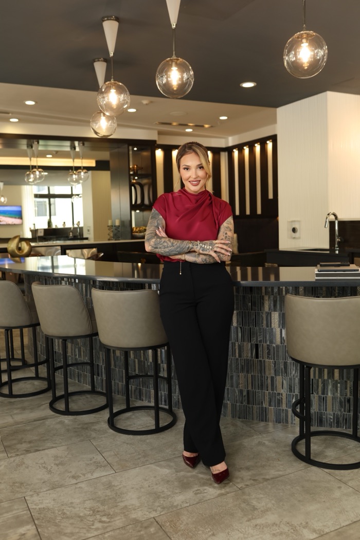 Agata standing composed at a dark stone bar in a luxury lounge