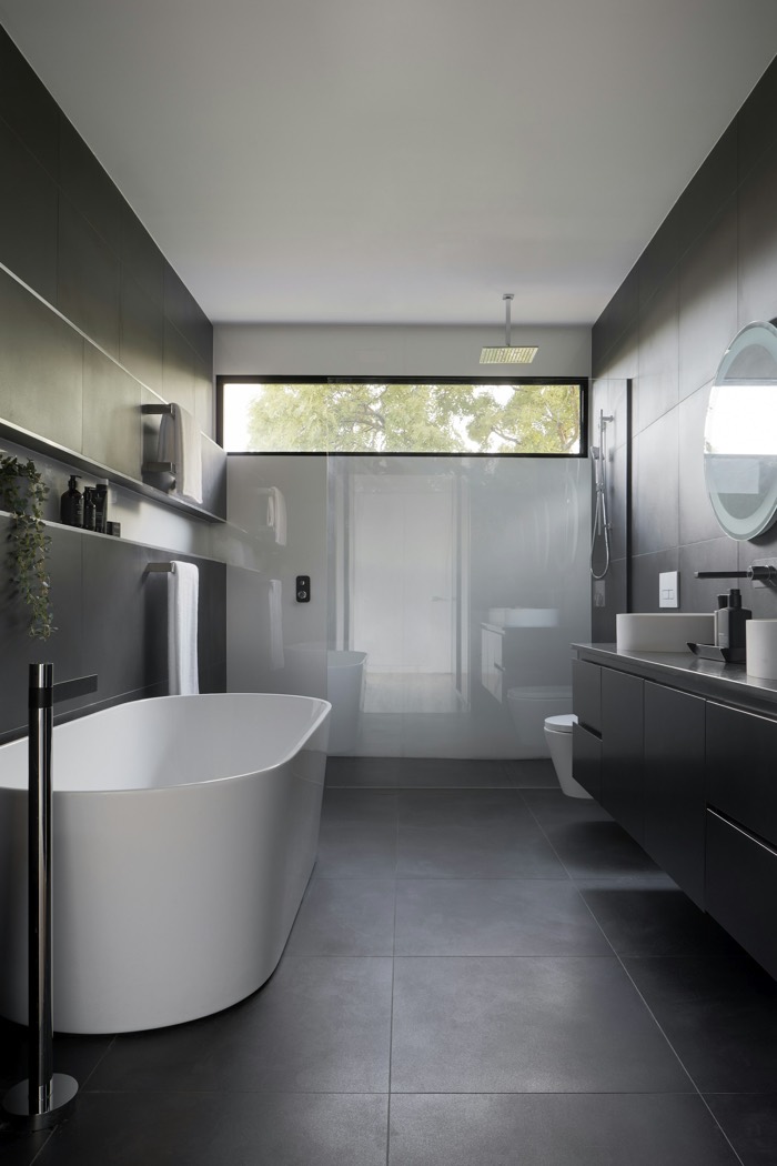 Stone-tiled bath suite with a freestanding tub and matte black fixtures