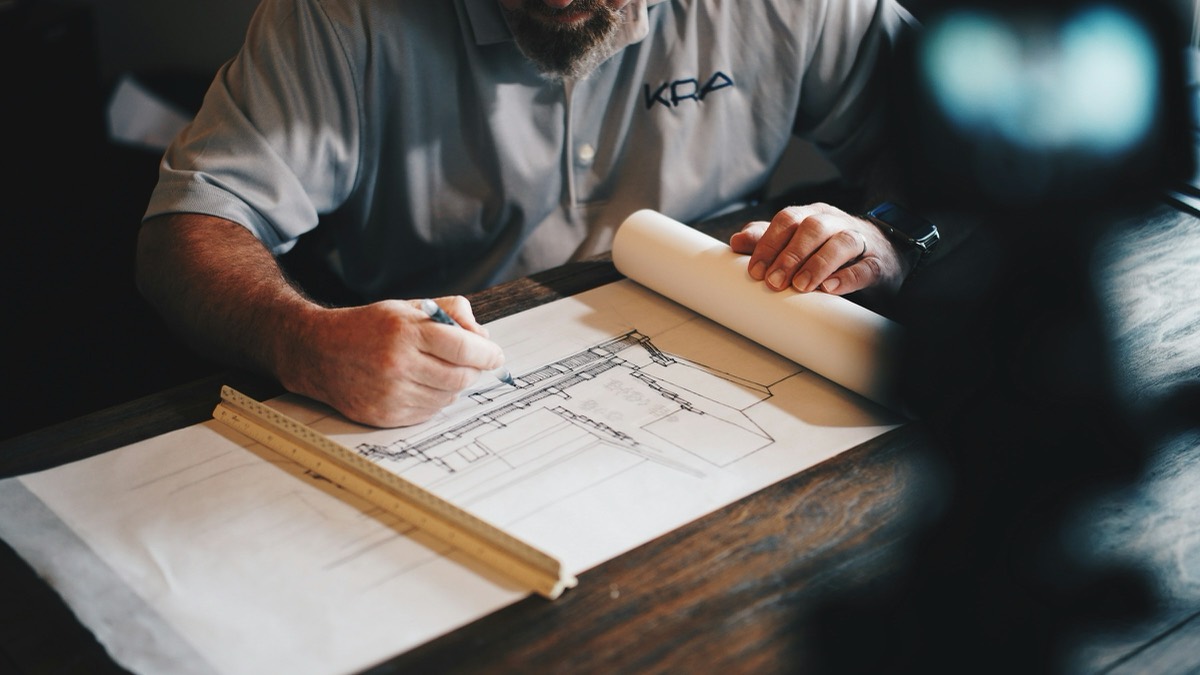 Architect drafting construction plans by hand at a work table